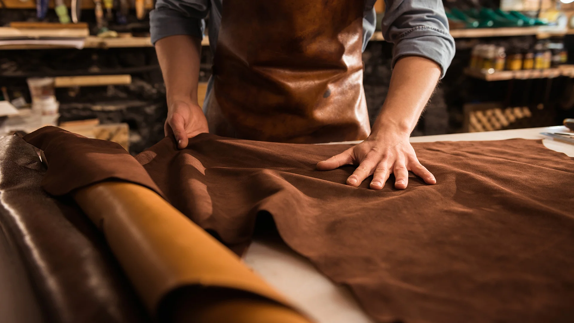 Artizan lucrând o bucată de piele într-un atelier de marochinărie.