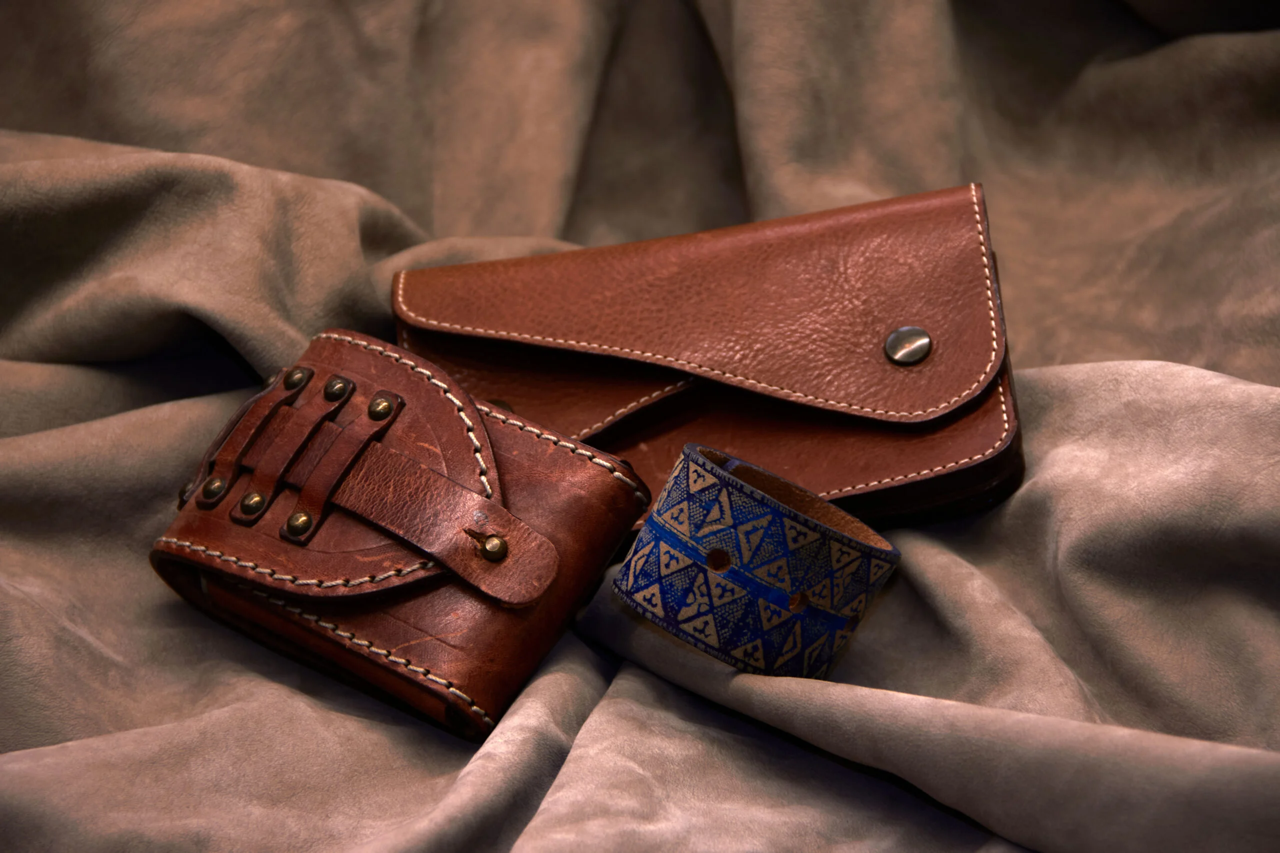 Articole Geronimo din piele: un etui maro, un portchei și un accesoriu cu model imprimat.