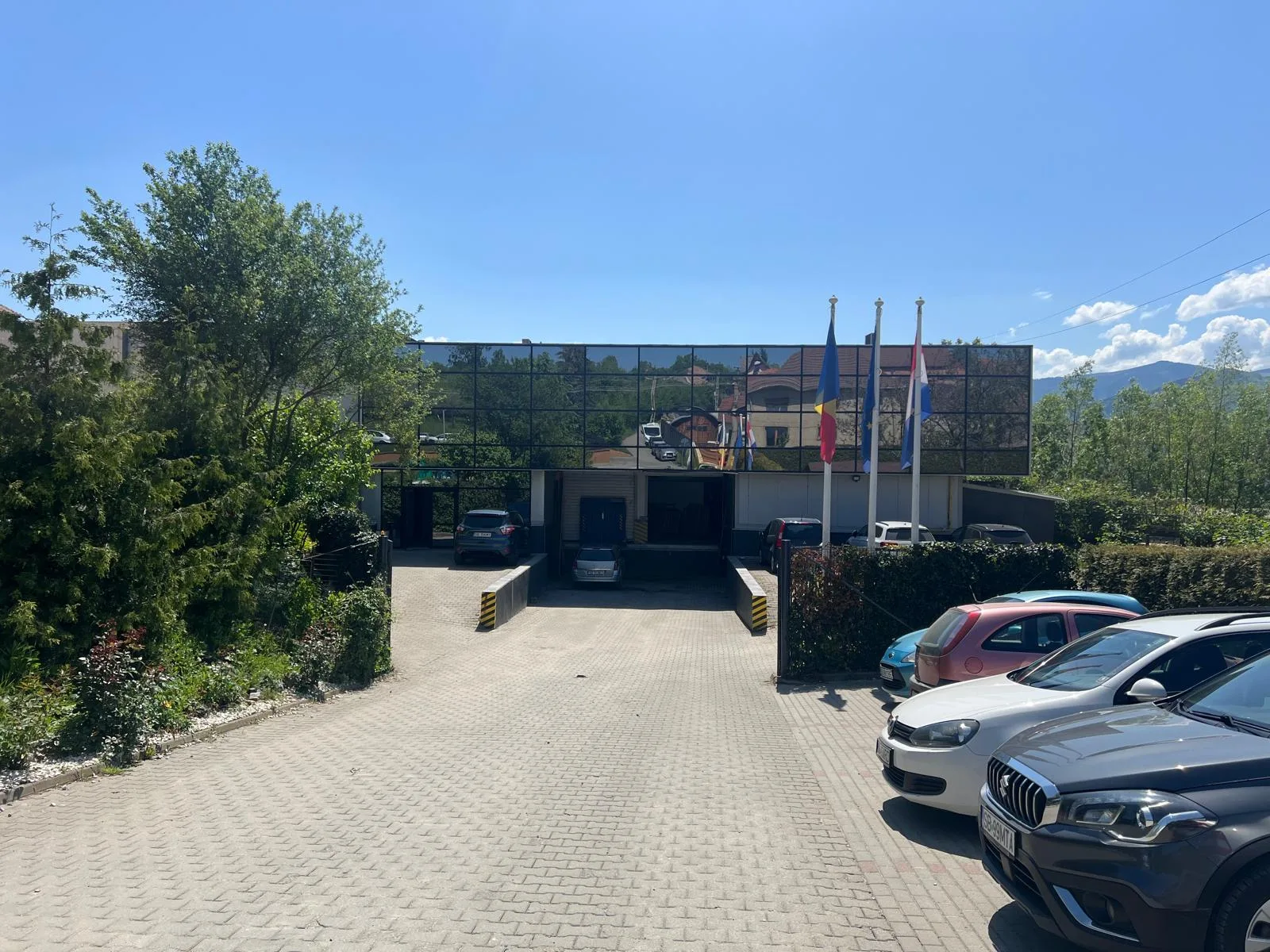 Exteriorul fabricii Geronimo din Cisnădie, cu intrarea principală, drapele și curtea din față.